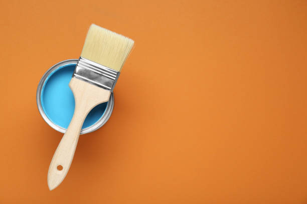 istock Can of light blue paint with brush on pale orange background, top view. Space for text 1901094284