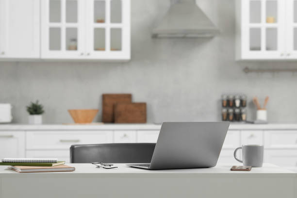 istock Home office. Laptop, glasses, smartphone and cup on white desk in kitchen, space for text 1901122555