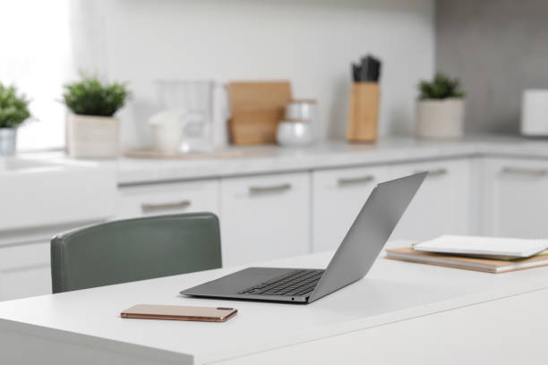 istock Home office. Laptop, smartphone and stationery on white desk in kitchen, space for text 1901123596