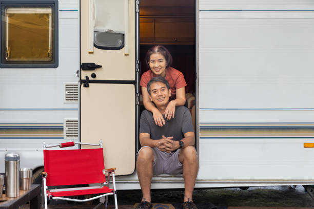 senior asian couple joyful and relax sitting in front of caravan home on vacation. - motor home mobile home camping senior adult photos et images de collection