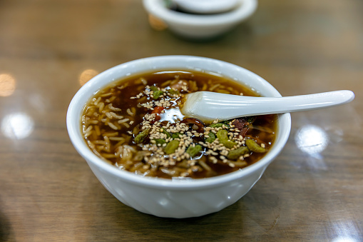 A bowl of sweet porridge lies on a glass table, characteristic of Chinese cuisine