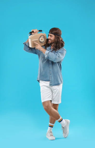 istock Stylish hippie man with retro radio receiver on light blue background 1901171888