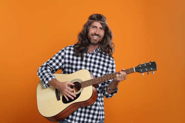 istock Hippie man playing guitar on orange background 1901181691