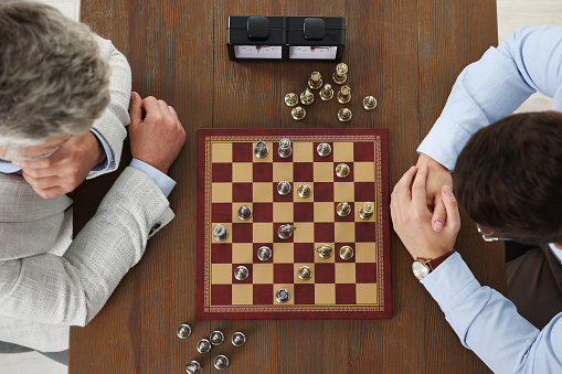 Men playing chess during tournament at wooden table, top view