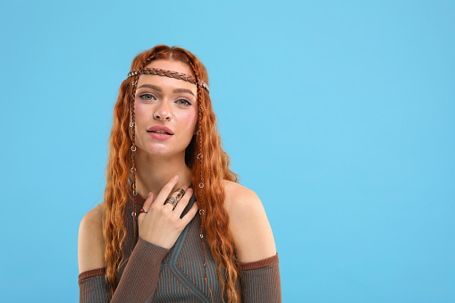 Beautiful young hippie woman on light blue background, space for text