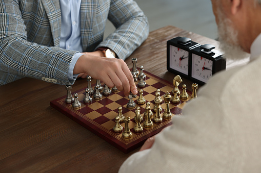 Men playing chess during tournament at wooden table, closeup