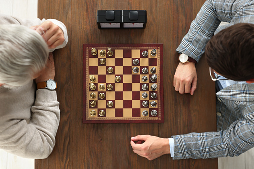 Men playing chess during tournament at wooden table, top view