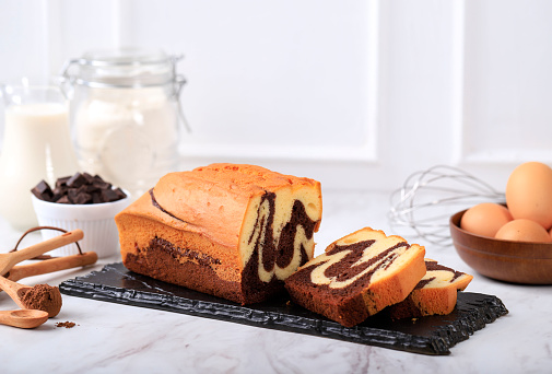 Concept White Background Bakery, Loaf Marble Cake Slice on Stone Black Plate with Ingredient at Background
