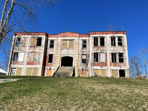 Cairo, West Virginia, USA - March 20, 2023: The ruins of the abandoned former Cairo High School on a sunny day.