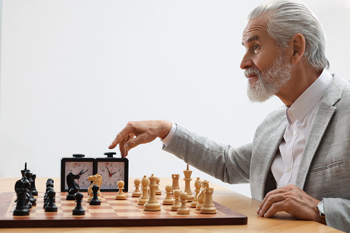 Man turning on chess clock during tournament at table against white background