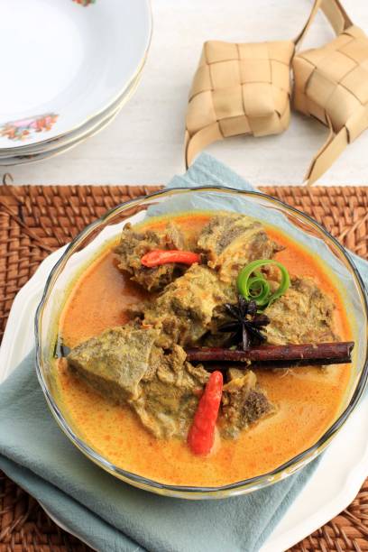 istock Gulai Sapi is Beef Curry Typically Traditional Food from Padang, West Sumatera, Indonesia. Served at the Table with Bowl and Ketupat Lebaran. Menu for Eid al Adha (Idul Adha) 1901303057