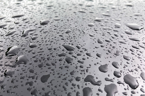 Large drops of water on a black glossy surface.