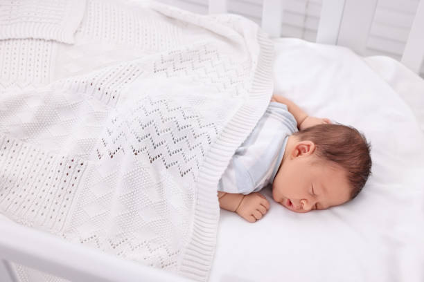 istock Cute newborn baby sleeping under plaid in crib 1901382255