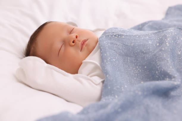 istock Cute newborn baby sleeping under blue blanket on bed, closeup 1901382257