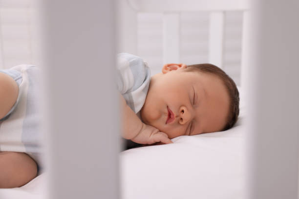 istock Cute newborn baby sleeping on white blanket in crib 1901382771