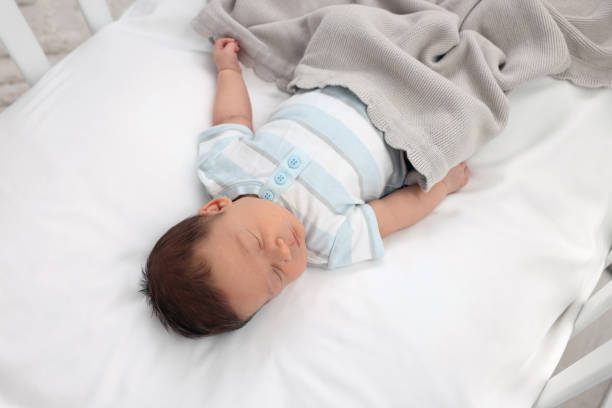 istock Cute newborn baby sleeping under blanket in crib. Bedtime 1901383287