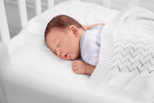 istock Cute newborn baby sleeping under plaid in crib 1901383290