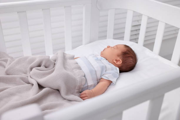 istock Cute newborn baby sleeping under blanket in crib. Bedtime 1901383794