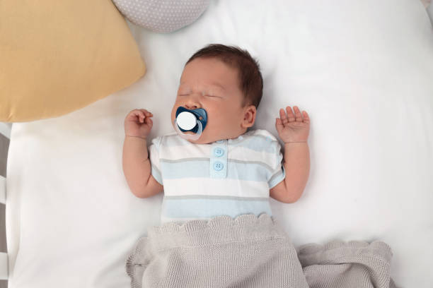 istock Cute newborn baby with pacifier sleeping under blanket in crib, top view. Bedtime 1901383795