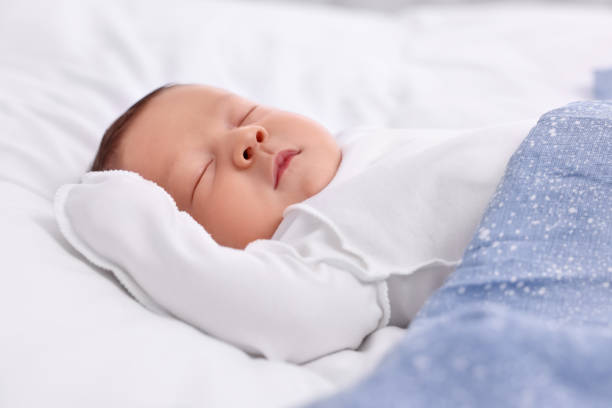 istock Cute newborn baby sleeping under blue blanket on bed, closeup 1901385374