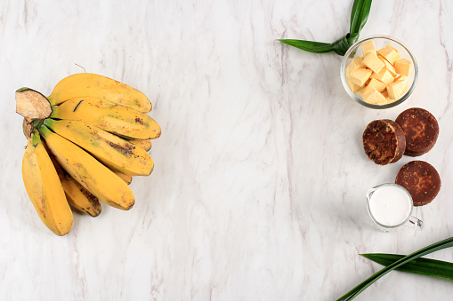 Top View Ingredient Preparation making Banana and Sweet Potato Compote (Kolak Pisang Ubi). Ripe Banana, Sweet Potato, Palm Sugar (Gula Merah), Pandan Leaves, and Coconut Milk. Popular for Ramadan