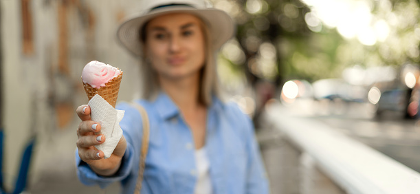 A woman traveling through Europe in the summer showing ice cream to the camera. Tourism and travel concept