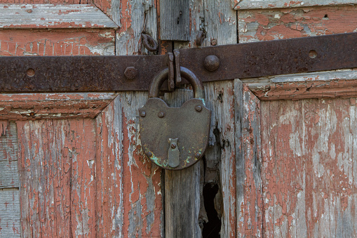 Old padlock on a wooden door. Whole background.