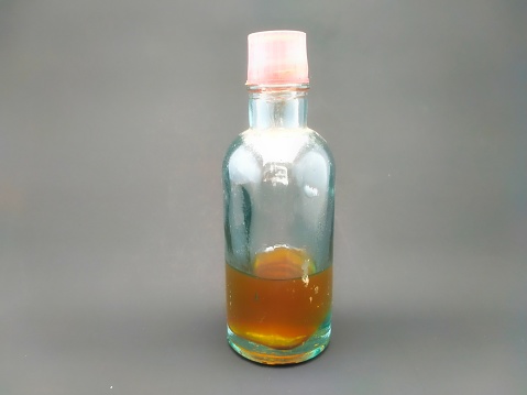 Traditional spreadable oil (as Minyak Telon) in a bottle with a dark background