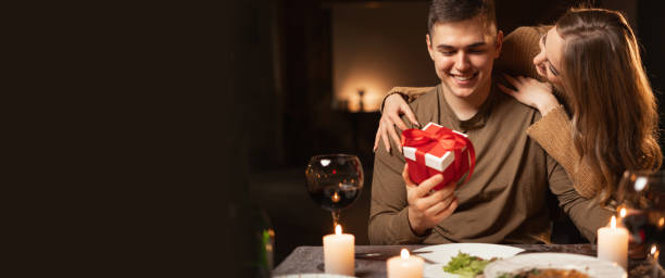 istock Romantic candlelight dinner for two, Valentine's Day date, authentic couple having dinner with a woman giving a gift to a man, romantic family relationship, Valentine's day celebration 1901435234