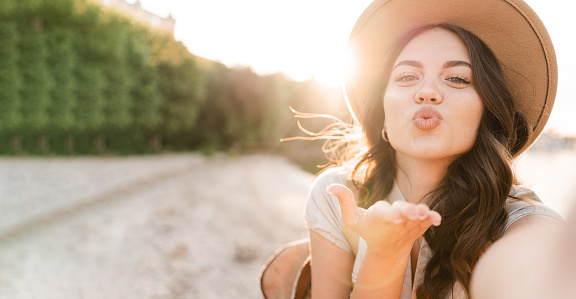 Girl tourist taking a selfie on the beach sending an air kiss to the camera records a video for her subscribers. Copy space