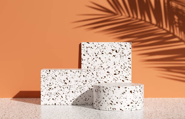 istock Product display setting with terazzo textured white podiums and tropical palm leaf shadow on orange colored background. 1901484583