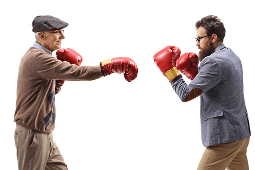 Elderly and younger man fighting with boxing gloves isolated on white background