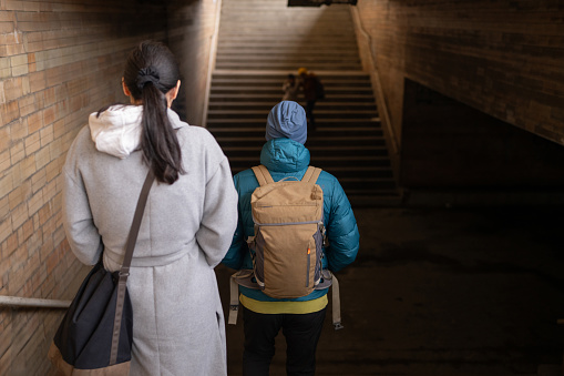 Back view of happy family walking down the stairs  on train station