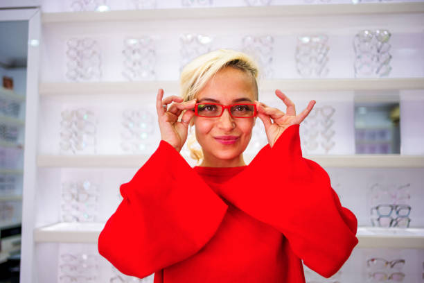 Smiling young woman trying on glasses, looking at camera