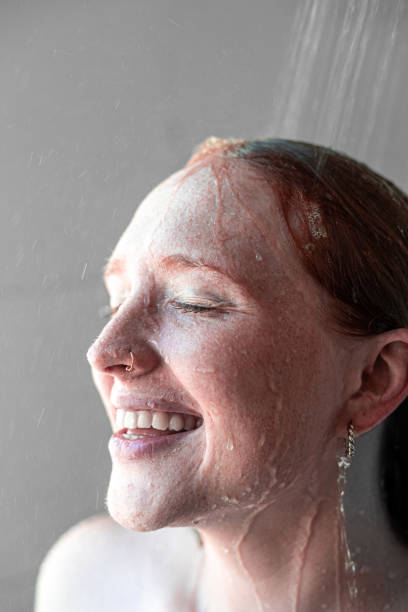 In an intimate moment captured within the shower's serenity, a redheaded beauty embraces the gentle cascade of water, her freckled skin adorned with natural splendor. The close-up reveals the exquisite details of her complexion, highlighted by delicate droplets glistening like diamonds against her porcelain skin. Each freckle tells a story, a testament to her natural allure and unfiltered beauty, as she indulges in the tranquil embrace of the shower's rejuvenating flow.