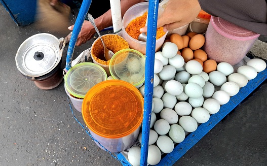 A view of Kerak Telor street snack stall while the seller is cooking. This Jakarta's traditional omelette is made of white glutinous rice, eggs, dried roasted shrimp, fried shallots, roasted shredded coconut, and spices.