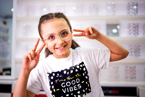 Smiling little girl trying on glasses