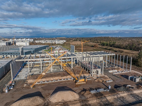Drone image of a construction site of an industrial building with columns and beams and a heavy-duty crane during the day