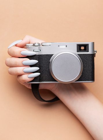Close up of woman's hand with grey nail polish holding camera