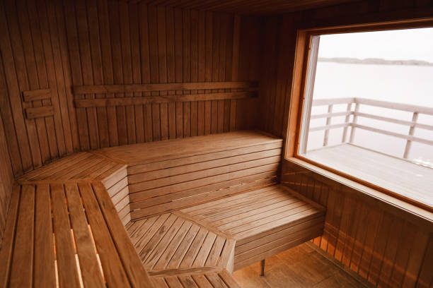 An empty dry sauna Photograph of the inside of an empty dry sauna with large windows. Walls and benches made of wood and a tile floor. swedish sauna stock pictures, royalty-free photos & images