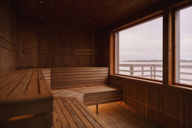 An empty dry sauna Photograph of the inside of an empty dry sauna with large windows. Walls and benches made of wood and a tile floor. swedish sauna stock pictures, royalty-free photos & images
