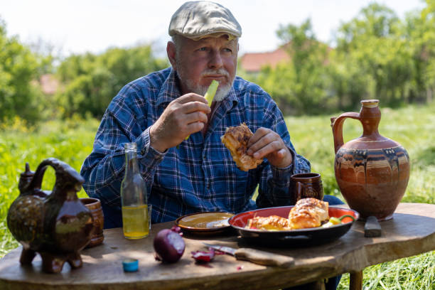 istock A farmer, an older man, is having breakfast, taking a break from mowing. 1901765198