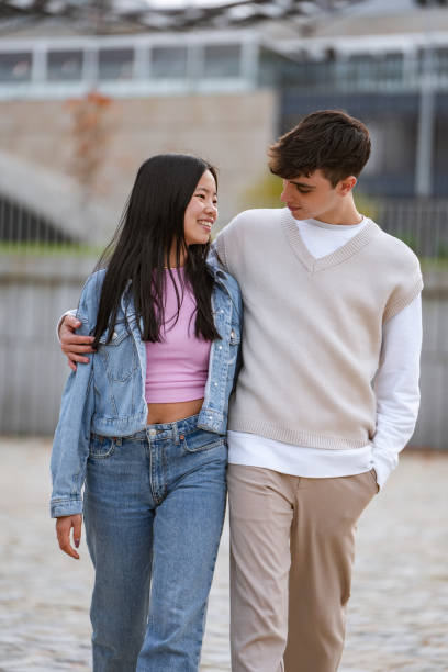 istock Young couple smiling while walking together outdoors. 1901774558