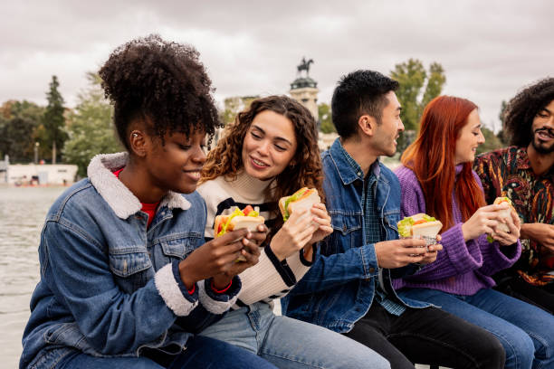 multicultural friends on university break eating a sandwich while laughing