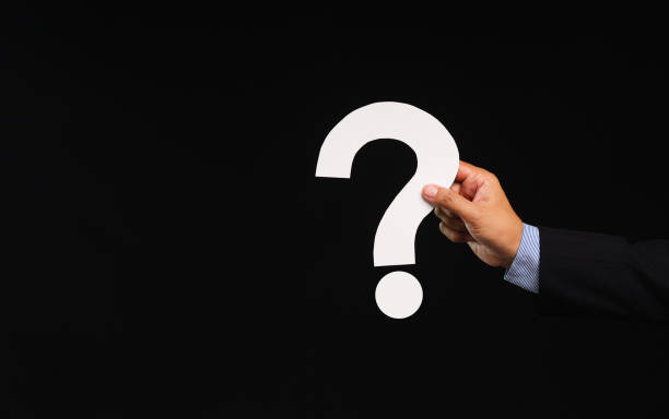 istock Hand holding a white question mark symbol against a black background. 1901802994