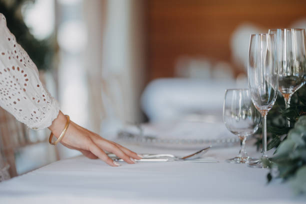 istock Woman preparing romantic table setting for indoor wedding reception. Luxury wedding table decoration, special event table set up with fresh flowers arragements. 1901806221