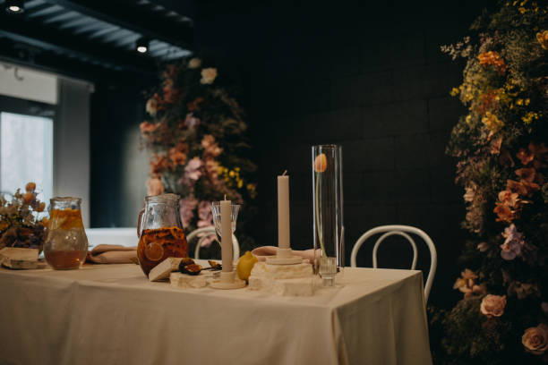 istock Elegant, clean and easy table setting for indoor party, wedding reception with luxury, big flower decoration on wall. Special event table set up with fresh flowers arragements. 1901807263