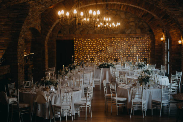 istock Elegant, romantic table setting for indoor wedding reception with fairy lights on wall behind. Winery, brewery cellar wedding venue. 1901810416