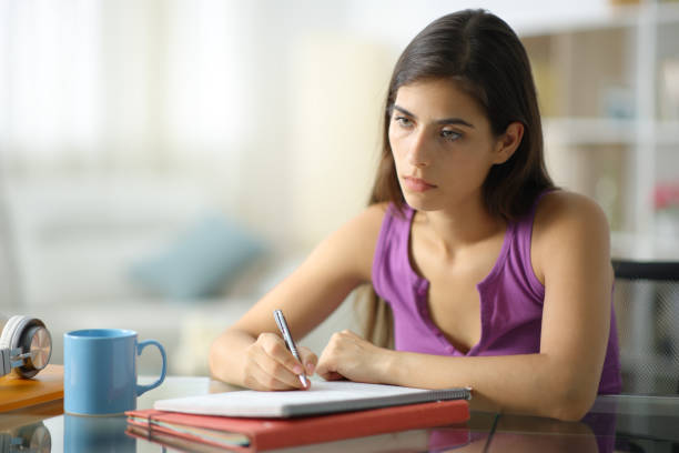 istock Demotivated and worried student taking notes looking away 1901837716