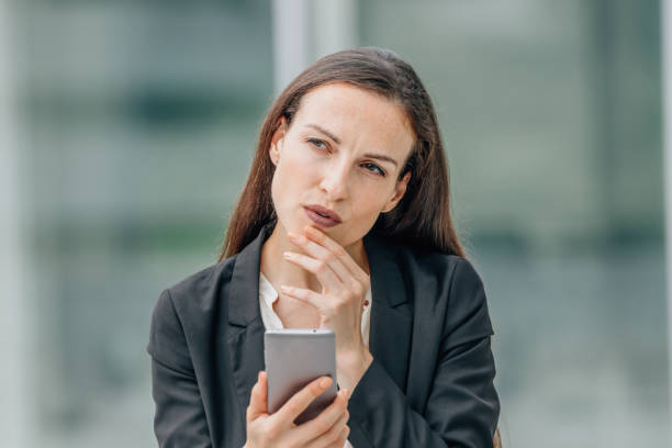 istock business woman with mobile phone thoughtful making decision 1901850373